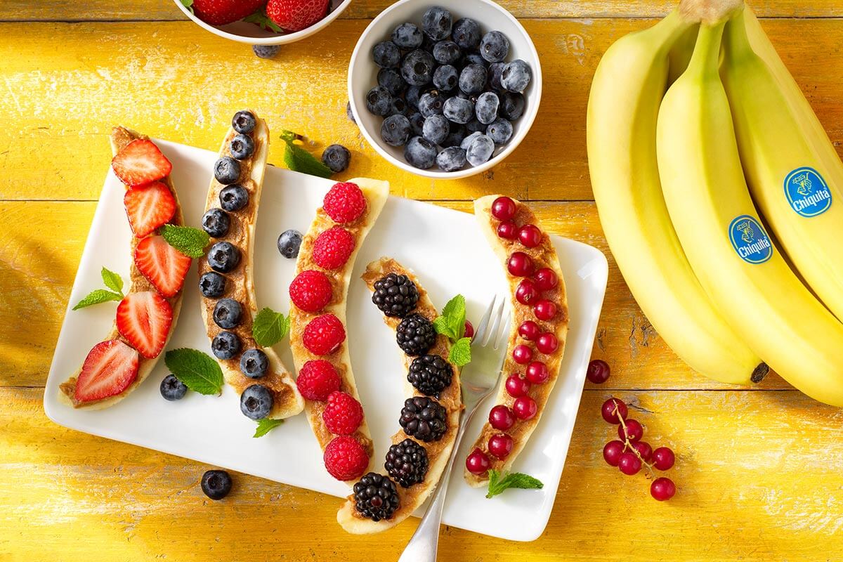 Colazione sana a base di banana split Chiquita con frutti rossi e burro di arachidi